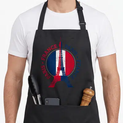 Tablier de cuisine noir avec une Tour Eiffel tricolore et les mots Paris France imprimés en cercle autour.