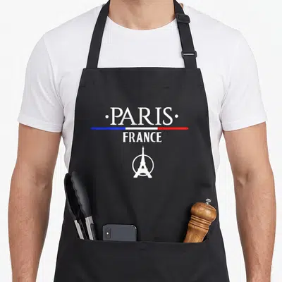 Tablier de cuisine noir avec inscription Paris France et logo Tour Eiffel sous une bande tricolore.