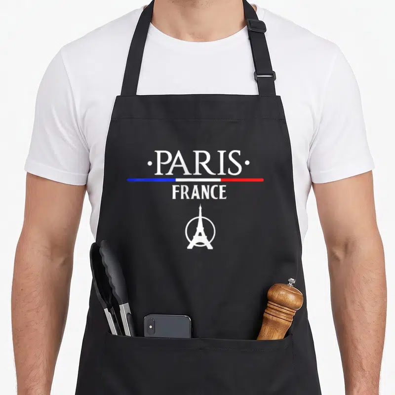 Tablier de cuisine noir avec inscription Paris France et logo Tour Eiffel sous une bande tricolore.