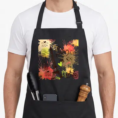 Tablier de cuisine noir avec une illustration colorée de Paris incluant la Tour Eiffel, un vélo et des textes comme Bonjour et Oh la la.