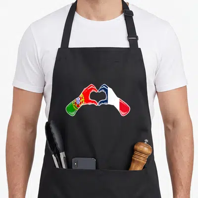 Tablier de cuisine noir avec deux mains formant un cœur, une imprimée du drapeau portugais et l'autre du drapeau français.