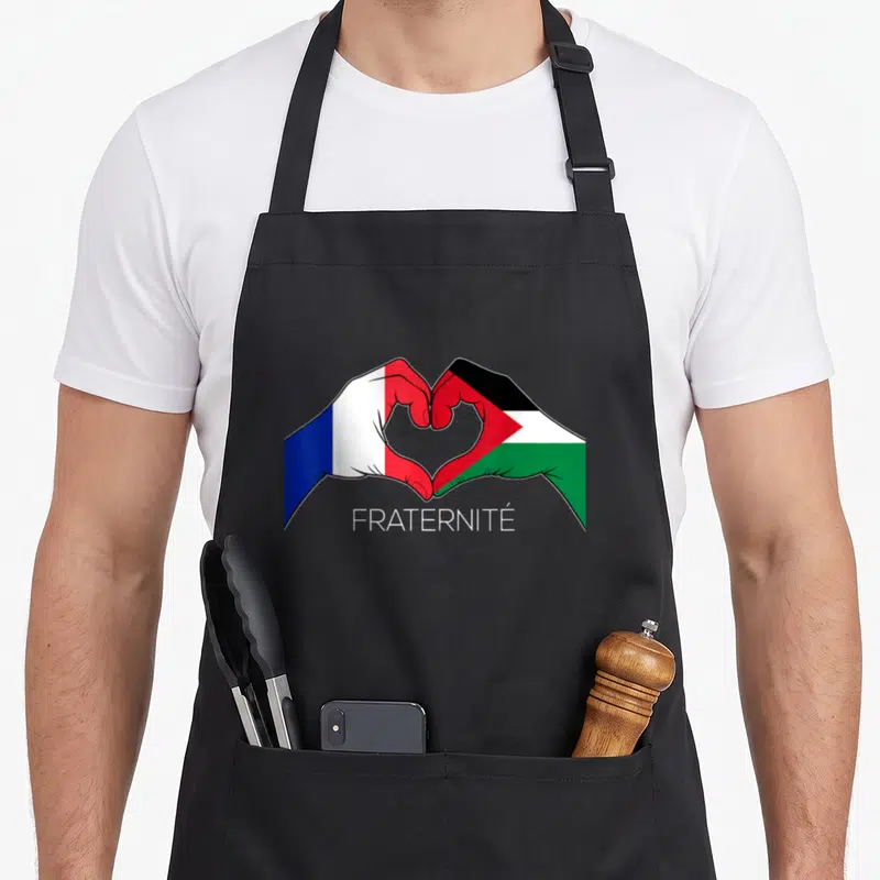 Tablier de cuisine noir avec deux mains aux couleurs des drapeaux français et palestinien formant un cœur au centre.
