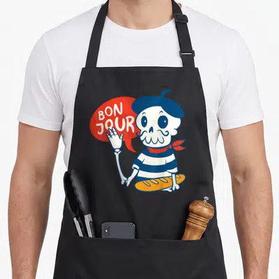 Tablier de cuisine noir avec un crâne en béret tenant une baguette et disant Bon Jour dans une bulle rouge.