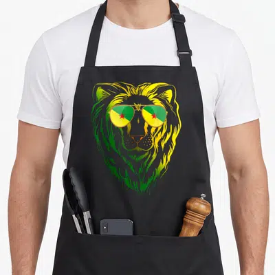 Tablier de cuisine noir avec un lion aux verres reflétant les couleurs vert jaune et rouge de la Guyane française