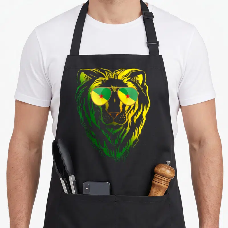 Tablier de cuisine noir avec un lion aux verres reflétant les couleurs vert jaune et rouge de la Guyane française