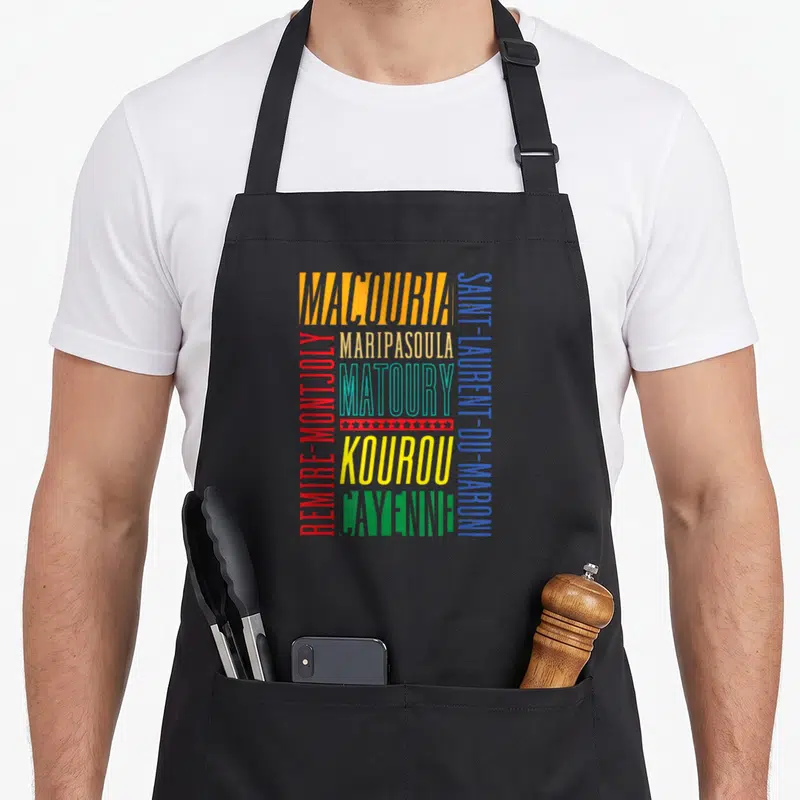 Tablier de cuisine noir avec les noms de villes de Guyane en lettres colorées verticales et horizontales.