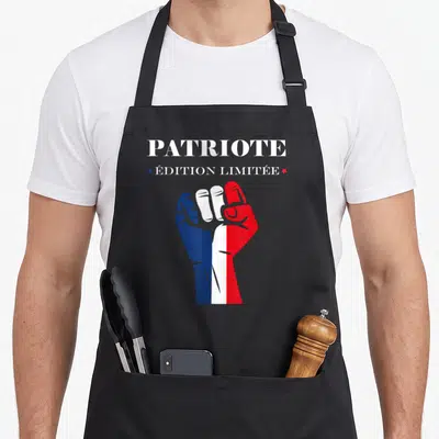 Tablier de cuisine noir avec un poing levé tricolore et l'inscription Patriote en haut.