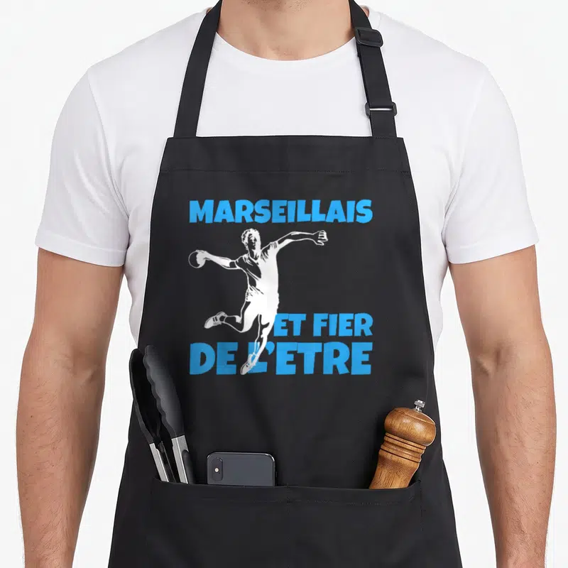 Tablier de cuisine noir avec illustration d'un sportif blanc et texte bleu Marseillais et fier de l'être.