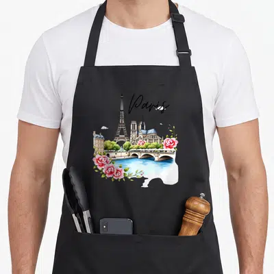 Tablier de cuisine noir avec illustration colorée de Paris incluant la Tour Eiffel, Notre-Dame, un pont sur la Seine et des roses roses.