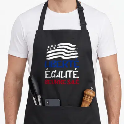 Tablier de cuisine noir avec drapeau stylisé et les mots Liberté Égalité Beurre Salé imprimés en bleu, blanc et rouge.