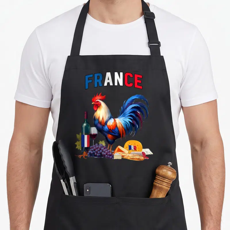 Tablier de cuisine noir avec un coq gaulois, du vin, des fromages et le mot France en lettres tricolores.