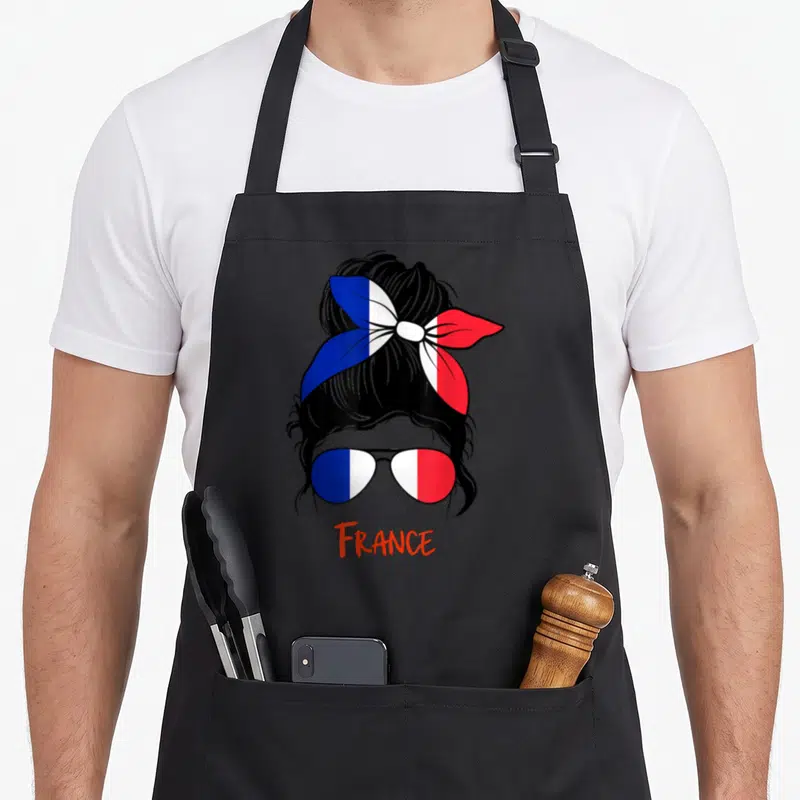 Tablier de cuisine noir avec une femme aux verres et chignon aux couleurs du drapeau français.