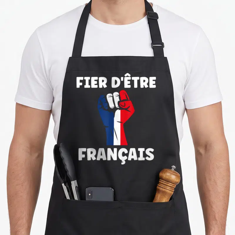Tablier de cuisine noir avec un poing tricolore et l'inscription fier d'être français en lettres blanches.