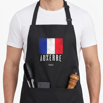 Tablier de cuisine noir avec drapeau français texturé et le mot Auxerre en lettres blanches contours noirs.