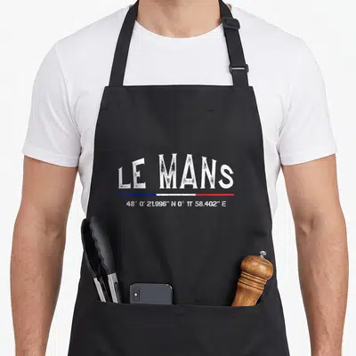 Tablier de cuisine noir avec inscription Le Mans, drapeau tricolore et coordonnées géographiques en blanc.