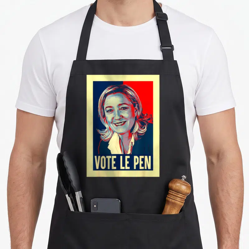 Tablier de cuisine noir avec illustration stylisée de Marine Le Pen et le texte vote le pen en bas.