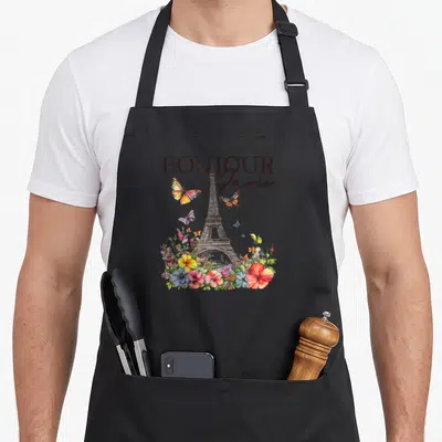 Tablier de cuisine noir avec illustration de la Tour Eiffel, Bonjour Paris, fleurs multicolores et papillons en vol autour du monument parisien.