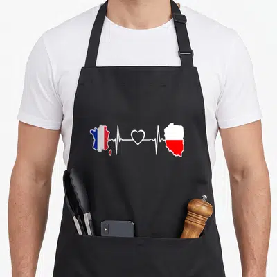 Tablier de cuisine noir avec carte de France et Pologne reliées par un motif de battement de cœur blanc.