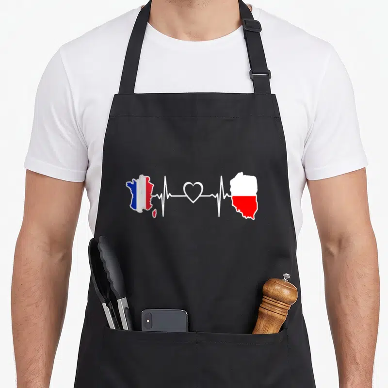 Tablier de cuisine noir avec carte de France et Pologne reliées par un motif de battement de cœur blanc.