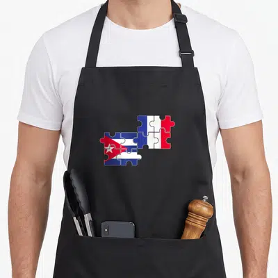 Tablier de cuisine noir avec drapeaux cubain et français formant un motif de puzzle au centre.