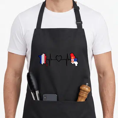 Tablier de cuisine noir avec carte de France et Serbie reliées par une ligne de rythme cardiaque et un cœur au centre.