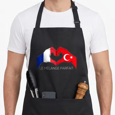 Tablier de cuisine noir avec deux mains formant un cœur aux couleurs des drapeaux français et turc.