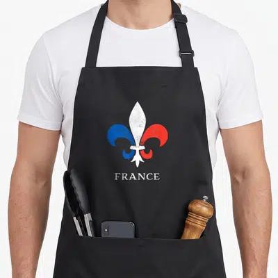 Tablier de cuisine noir avec une fleur de lys bleue rouge et blanche et le mot FRANCE imprimé en dessous.