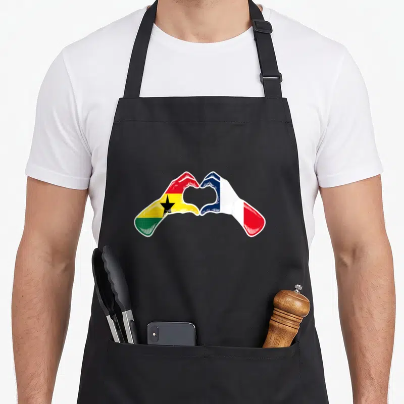 Tablier de cuisine noir avec deux mains formant un cœur, l'une au drapeau ghanéen et l'autre français.