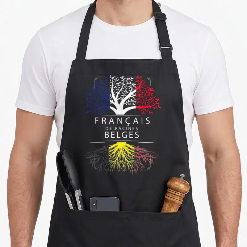 Tablier de cuisine noir avec un arbre aux branches tricolores et racines aux couleurs du drapeau belge, surmonté du texte français de racines belges.