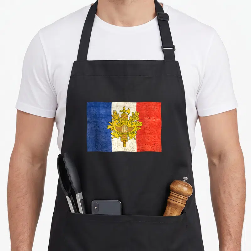 Tablier de cuisine noir avec le drapeau français et les armoiries de la République imprimés en style vintage au centre.