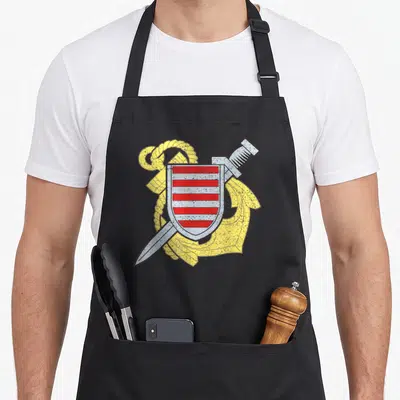 Tablier de cuisine noir avec un blason rouge et blanc croisé d'un couteau et d'une ancre jaune.