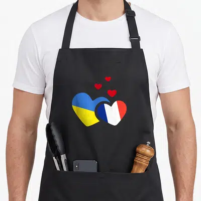 Tablier de cuisine noir avec deux cœurs aux drapeaux ukrainien et français et trois petits cœurs rouges.