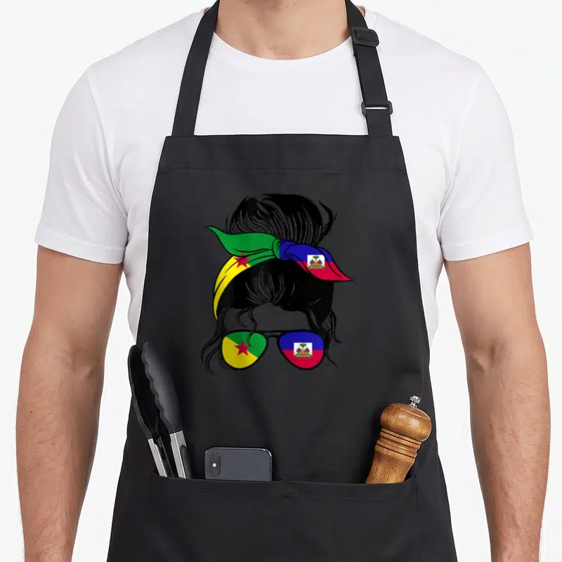 Tablier de cuisine noir avec illustration d'un profil féminin au bandana et lunettes aux couleurs des drapeaux guyanais et haïtiens.