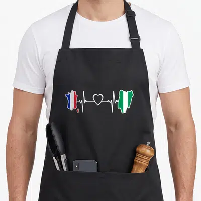 Tablier de cuisine noir avec carte France et Nigeria reliées par un motif de rythme cardiaque blanc.