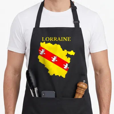 Tablier de cuisine noir avec carte jaune de la Lorraine et drapeau rouge à trois aigles blancs stylisés.
