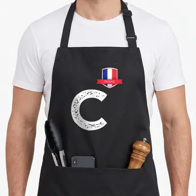 Tablier de cuisine noir avec grande lettre C blanche texturée et écusson drapeau FRANCE en haut à droite.
