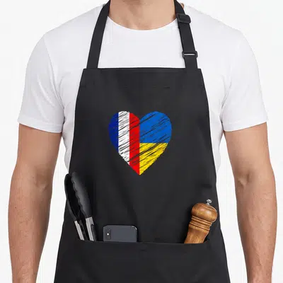 Tablier de cuisine noir avec un cœur stylisé aux couleurs des drapeaux français et ukrainien tracé au trait.