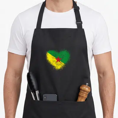 Tablier de cuisine noir avec un cœur formé par les couleurs du drapeau de la Guyane et une étoile rouge centrale.
