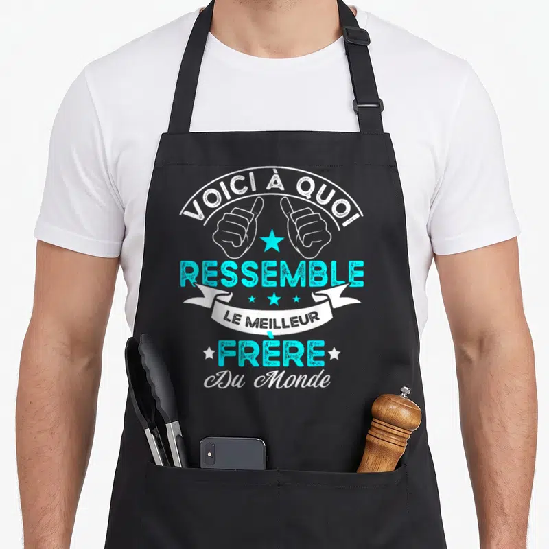 Tablier de cuisine noir avec inscription Voici à quoi ressemble le meilleur Frère du Monde et deux pouces levés bleus.