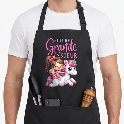 Tablier de cuisine noir avec illustration d'une enfant, d'un bébé et d'une licorne colorée sur le devant.