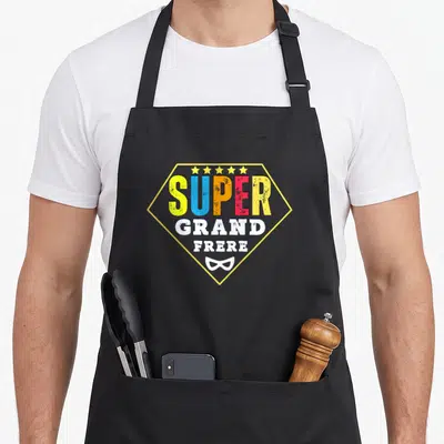 Tablier de cuisine noir avec logo Super Grand Frère multicolore, étoiles dorées et masque de super-héros blanc.