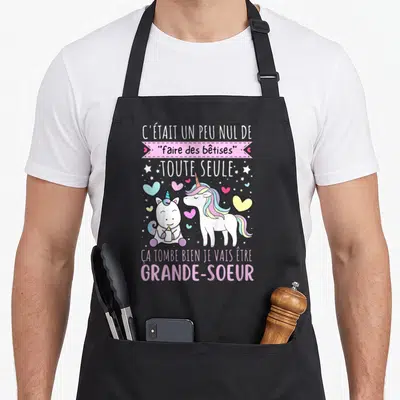 Tablier de cuisine noir avec deux licornes roses et le texte C était un peu nul de faire des bêtises toute seule.