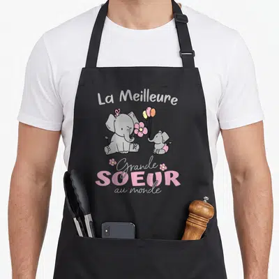 Tablier de cuisine noir avec deux éléphants gris, des fleurs roses et le texte La Meilleure Grande Soeur au monde.