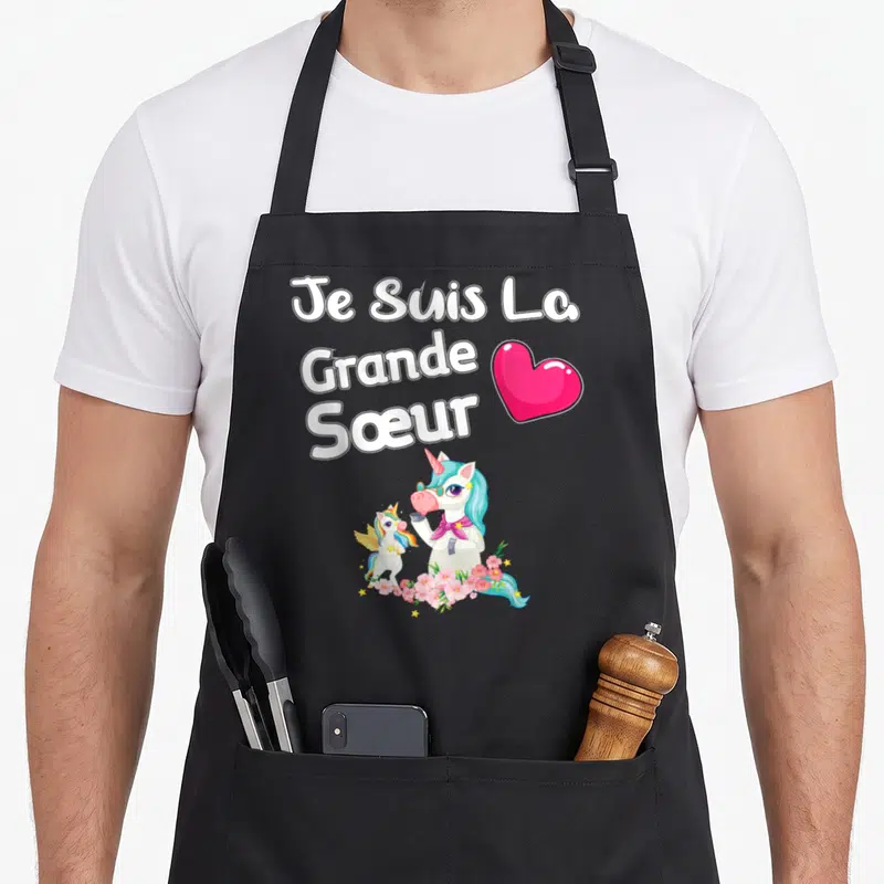 Tablier de cuisine noir avec une licorne turquoise, un pégase et le texte Je Suis La Grande Soeur Cadeau entouré de fleurs roses.
