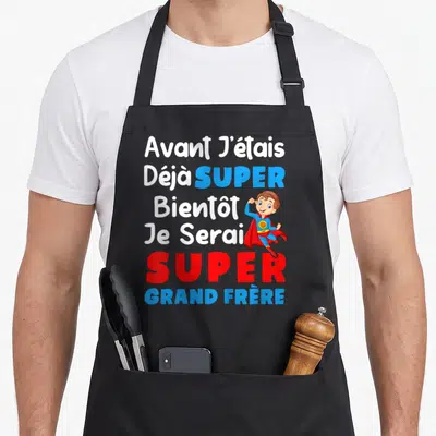Tablier de cuisine noir avec inscription blanche et rouge sur le thème du futur grand frère et un dessin de super-héros.