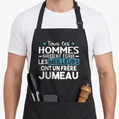 Tablier de cuisine noir avec inscription Tous les hommes naissent égaux les meilleurs ont un frère jumeau en blanc et bleu.