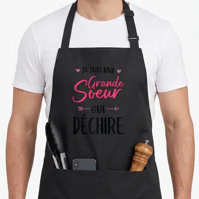 Tablier de cuisine noir avec inscription Je Suis Une Grande Soeur Qui Déchire en rose et noir.