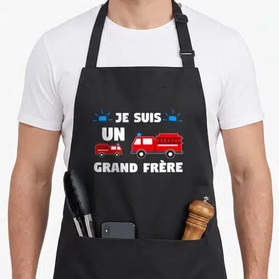 Tablier de cuisine noir avec inscription Je Suis Un Grand Frère 2021 et illustrations de pompiers et camions rouges.