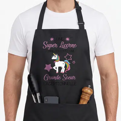 Tablier de cuisine noir avec une licorne colorée et l'inscription Une super licorne donne toujours une grande soeur exceptionnelle.