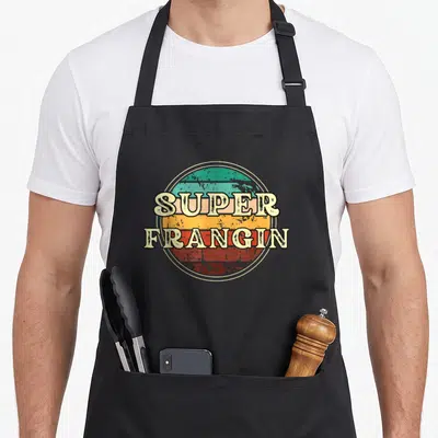 Tablier de cuisine noir avec inscription Super Frangin sur un cercle aux bandes horizontales colorées et texture dégradée.
